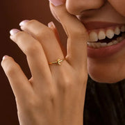 Close-up of a hand wearing a 14k gold filled crescent ring with a dark background